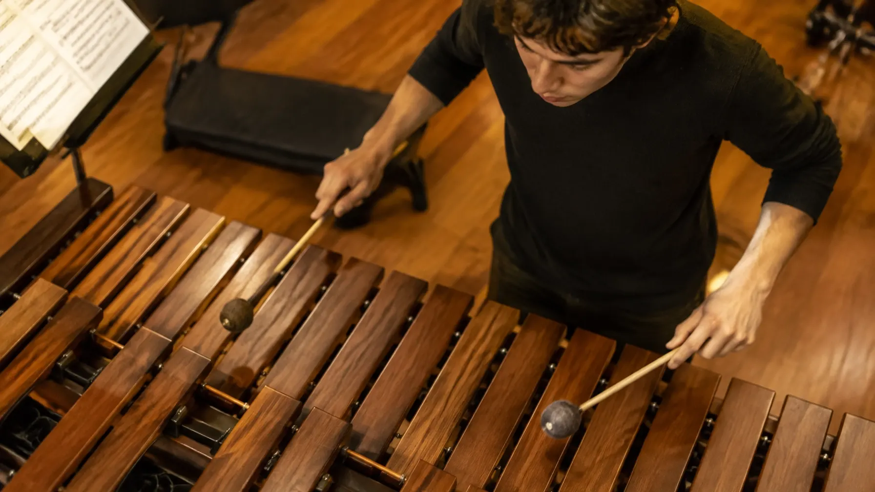Estudiante toca marimba mientras observa las teclas y sus manos